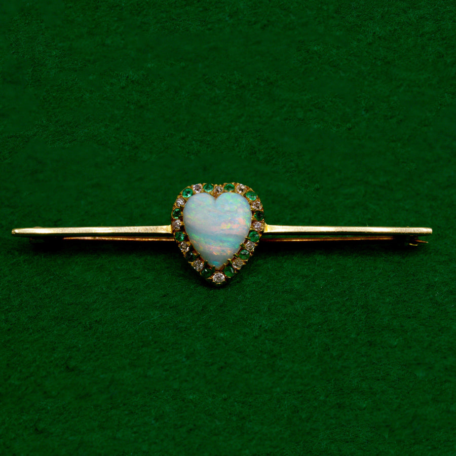 Victorian 18ct gold bar brooch with heart-shaped opal, diamonds and emeralds, vintage jewelry on green background.