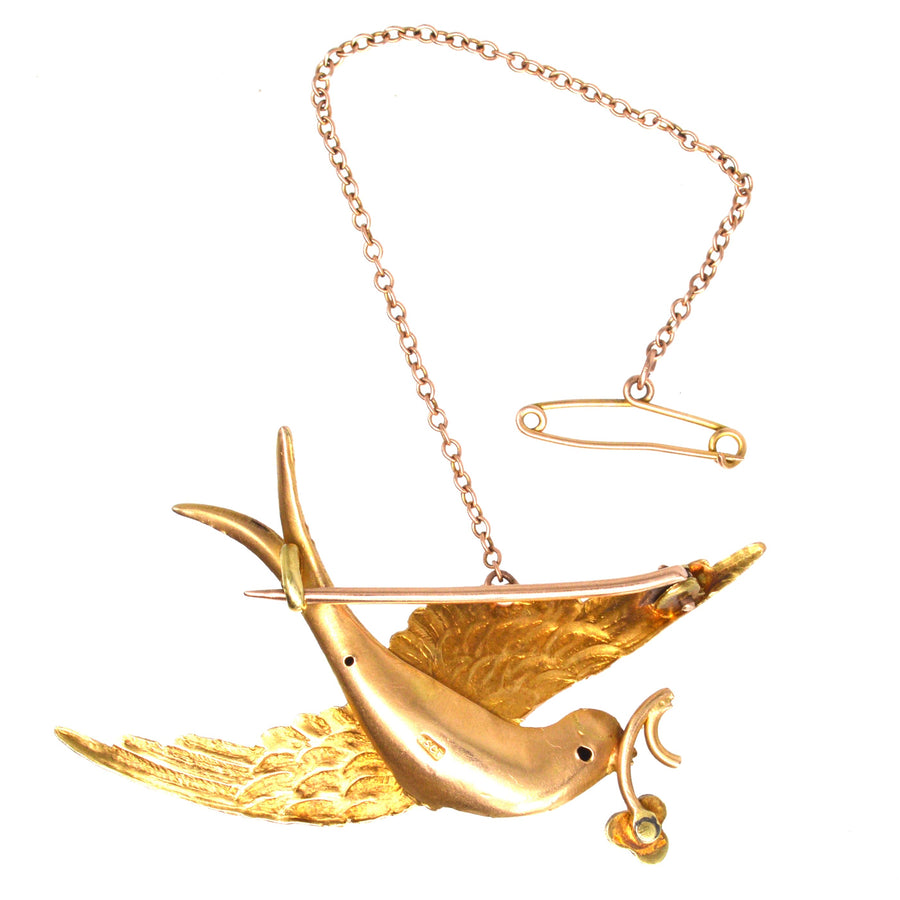 Victorian 15ct gold swallow brooch with filigree details and pearl flower accent, a symbol of love and renewal.