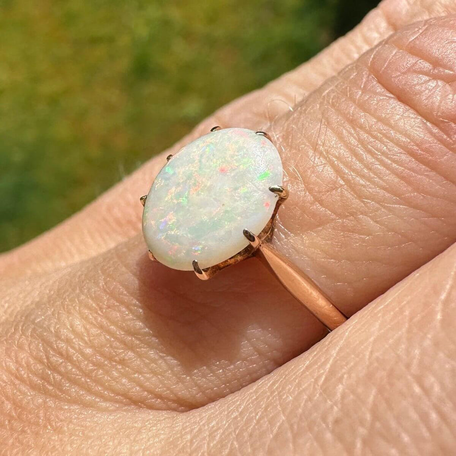 Art Deco 18ct gold ring featuring a stunning white opal with vibrant red, green, blue, and yellow hues.