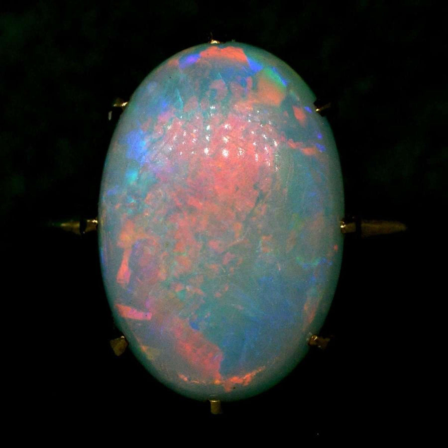 Art Deco ring featuring a stunning white opal with vivid red, green, blue, and yellow flashes in 18ct gold setting.