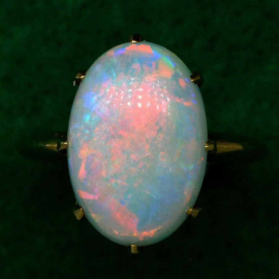 Art Deco 18ct gold ring featuring a vibrant opal with vivid red, green, blue, and yellow flashes of color.