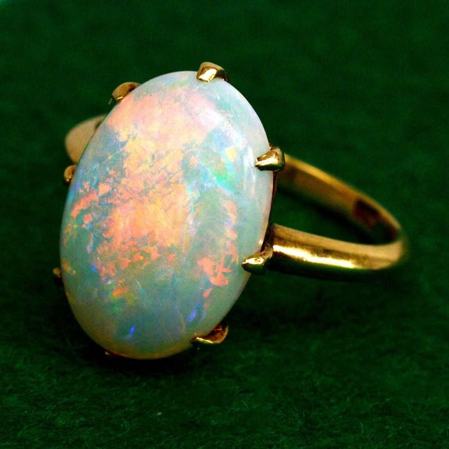 Art Deco 18ct gold opal ring featuring vivid red, blue, and green colors with a dazzling white opal centerpiece.