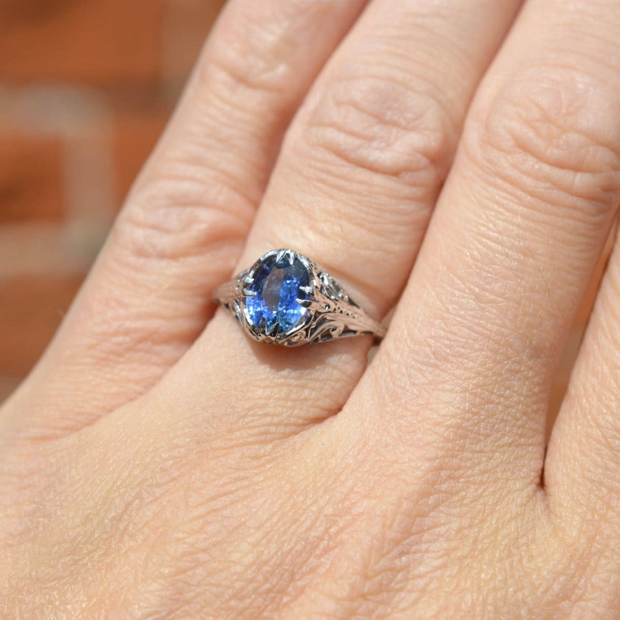 Belle Époque 18ct white gold ring featuring a cornflower blue sapphire on a hand.