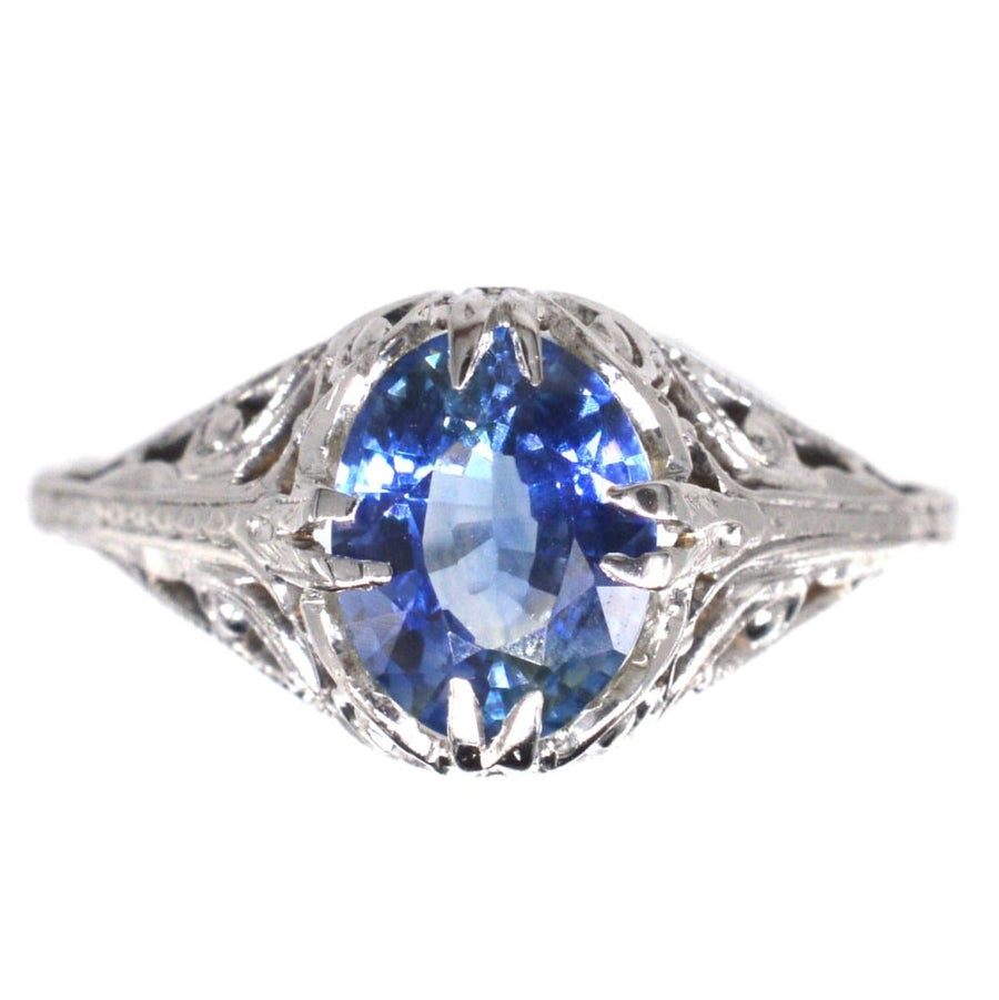 Belle Époque 18ct white gold ring featuring a cornflower blue sapphire in an intricate foliate design.