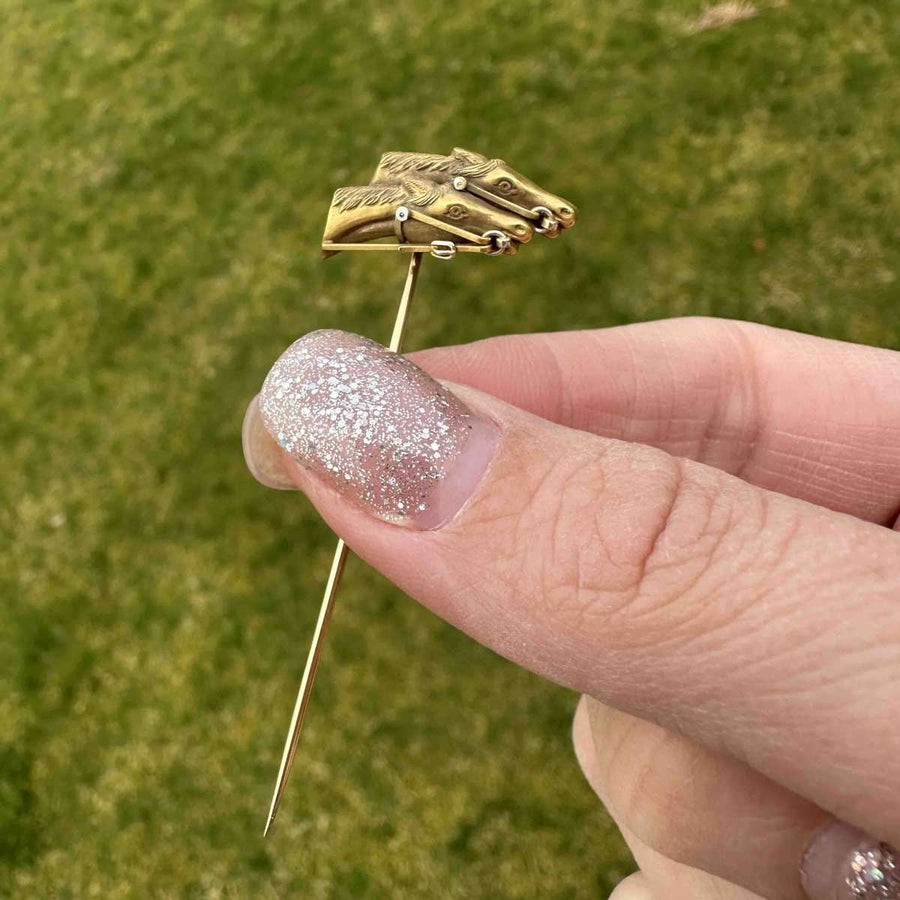 Edwardian 18ct gold racing horse tie pin held in hand, showcasing intricate horse head design.