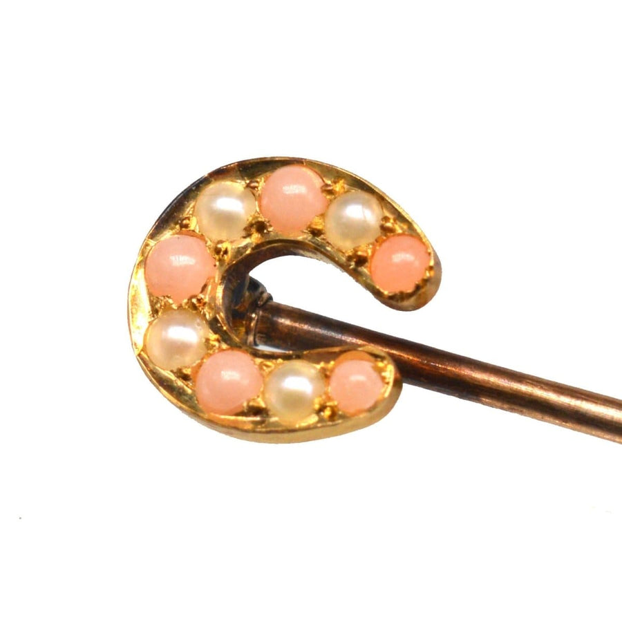 9ct gold horseshoe tie pin adorned with pearls and angel skin coral, symbolizing luck and protection.