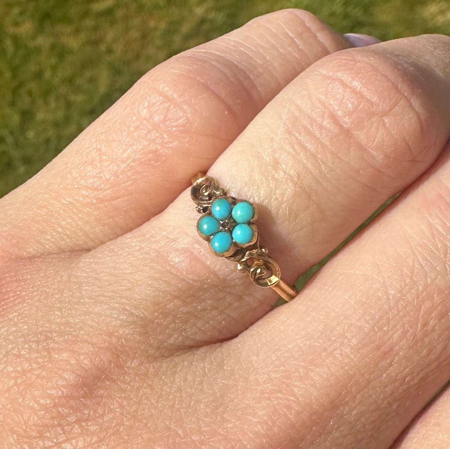 Georgian William IV 18ct gold ring featuring a cluster of turquoise flowers on a hand.