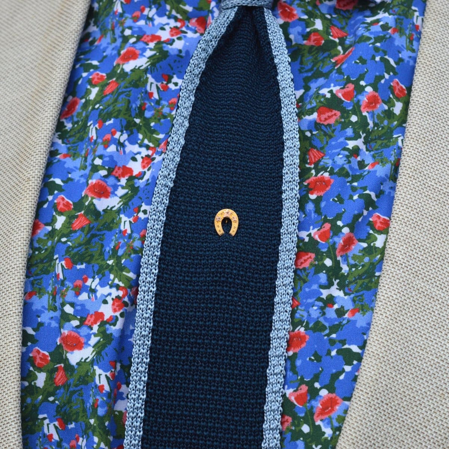 Late Victorian 9ct gold horseshoe tie pin on a floral patterned shirt, symbolizing luck and devotion.