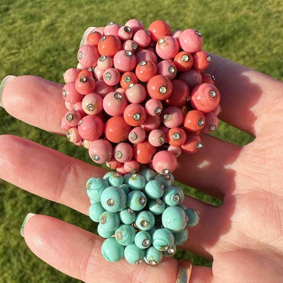 Rare Gripoix brooch featuring coral and blue turquoise glass paste with rhinestones on a hand