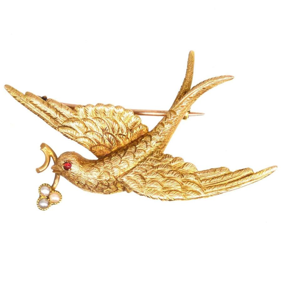 Victorian 15ct gold swallow brooch with seed pearl flower, symbolizing love and renewal.