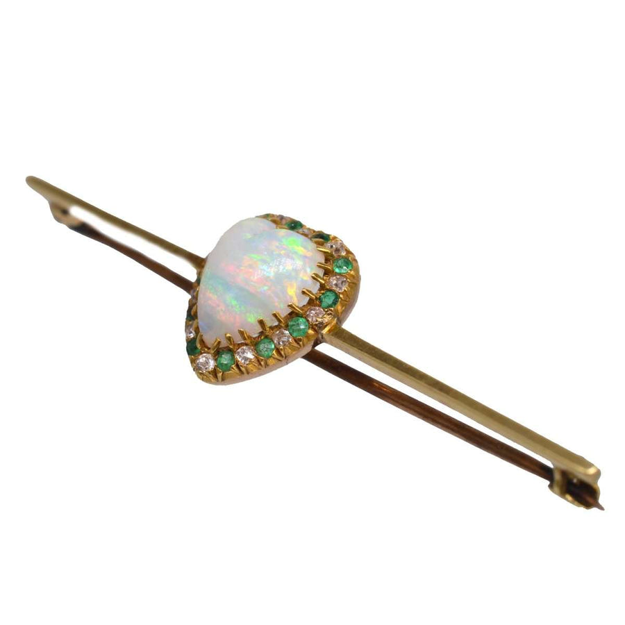 Victorian 18ct gold bar brooch featuring a heart-shaped opal surrounded by emeralds and diamonds.