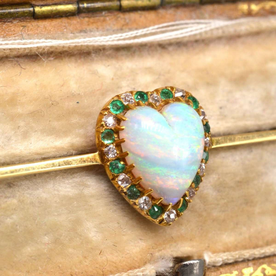 Victorian 18ct gold bar brooch featuring a heart-shaped opal surrounded by diamonds and emeralds.