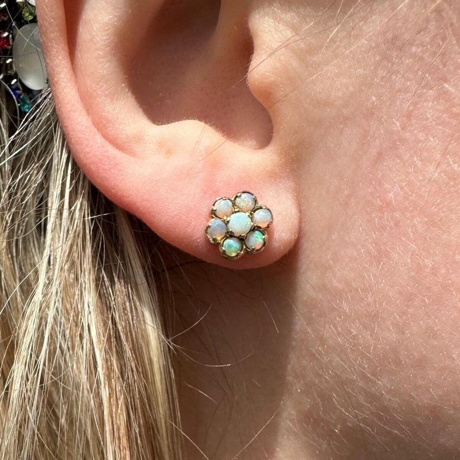 Vintage 9ct gold opal cluster stud earrings showcasing soft flashes of color on an ear.