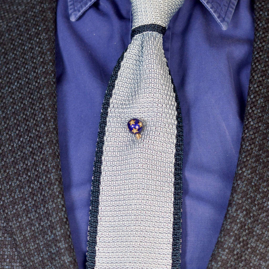 18ct gold tie pin featuring royal blue enamel and diamond star design, worn on a textured silver tie.