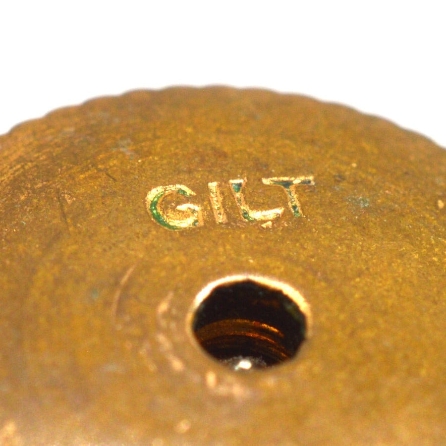 Close-up of the 'GILT' engraving on a 1930s Art Deco cufflink, showcasing vintage craftsmanship.