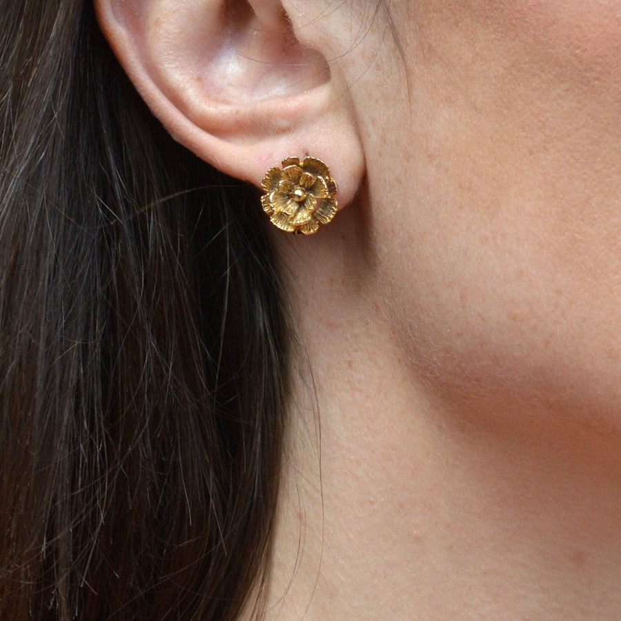 1940s 9ct gold flower clip-on earrings, detailed floral design, displayed on a model's ear.