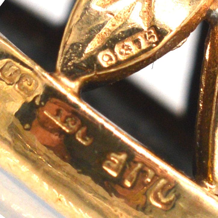 Close-up of hallmarks on a 1940's 9ct gold pendant, showcasing artisan craftsmanship and quality.