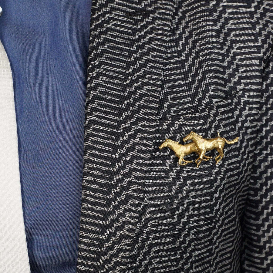 1940s 9ct gold brooch featuring two galloping horses on a patterned fabric, showcasing elegance and craftsmanship.