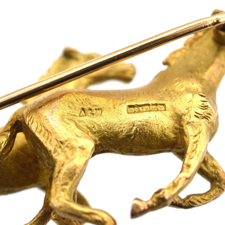 Close-up of a 1940s 9ct gold brooch featuring two galloping horses by Alabaster & Wilson.
