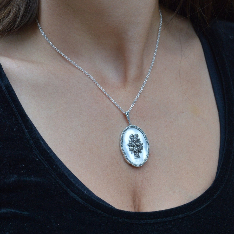 1940s silver pendant with mother of pearl and marcasite, featuring a floral design on a delicate chain.