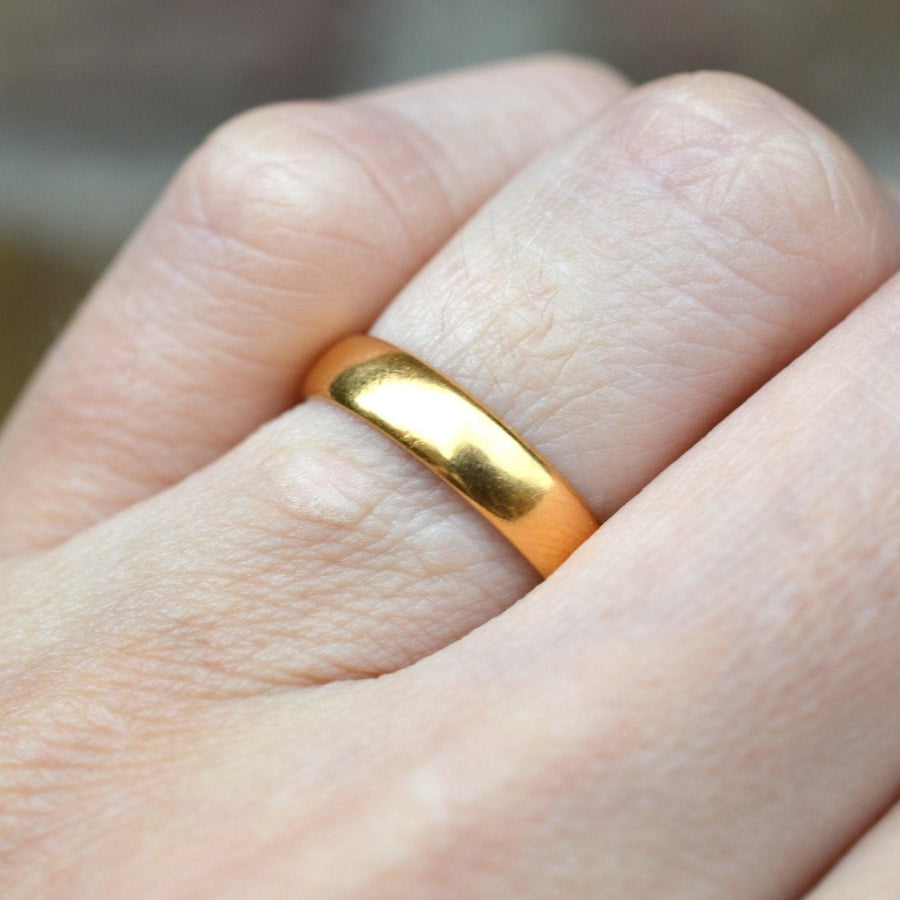 22ct gold wedding ring from the 1950s, displaying a smooth, buttery gold finish on a hand.