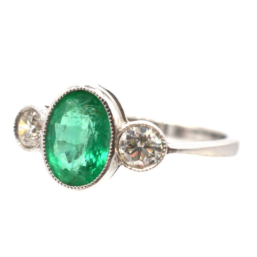 1950s platinum bezel ring featuring a 1 carat apple green emerald and two brilliant diamonds.