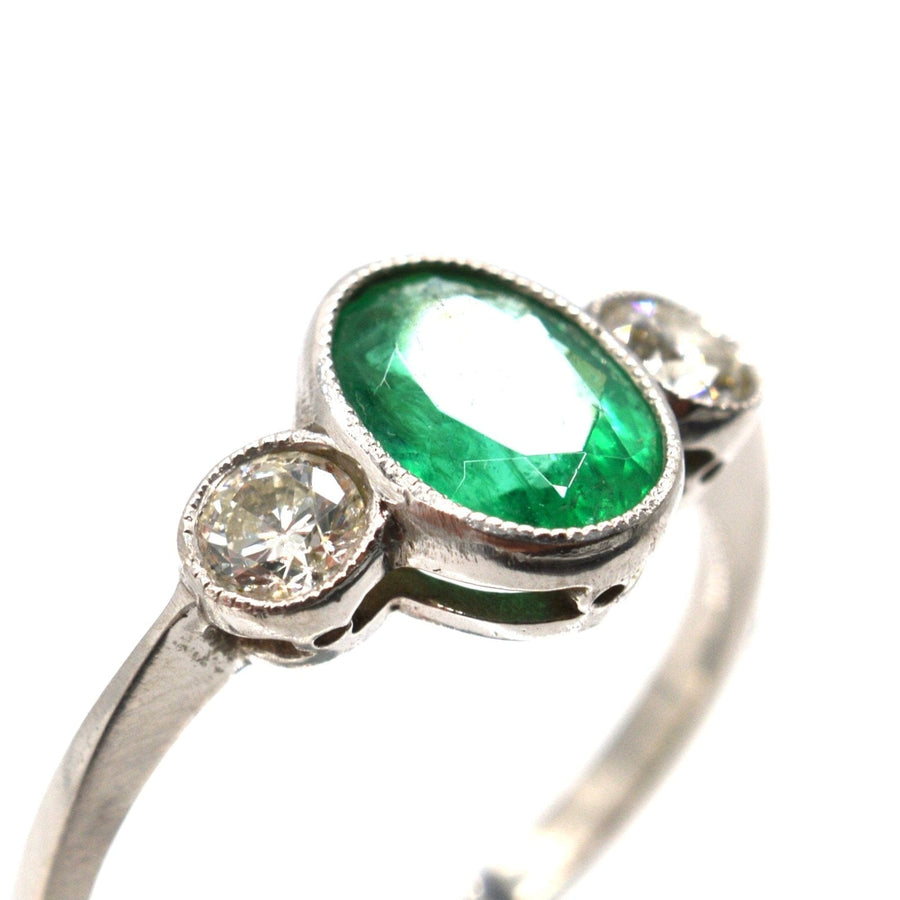 1950s vintage platinum ring featuring a 1-carat emerald and two bright diamonds, perfect for engagement or anniversary.
