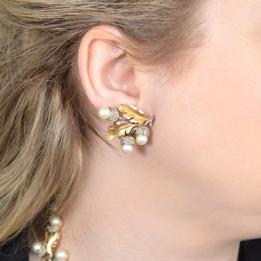 Vintage Trifari gold-tone oak leaf earrings with faux pearls and rhinestone acorns, showcased on a model.