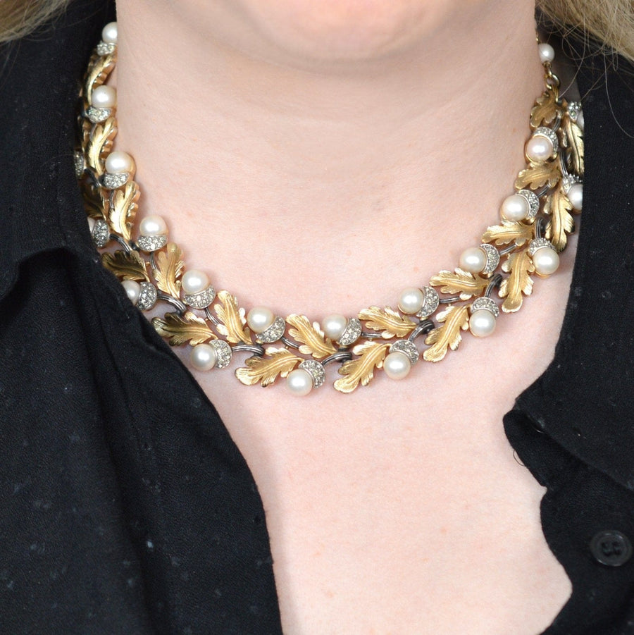 Vintage 1950s Trifari gold-tone oak leaf necklace with faux pearls and rhinestones on a model's neck.