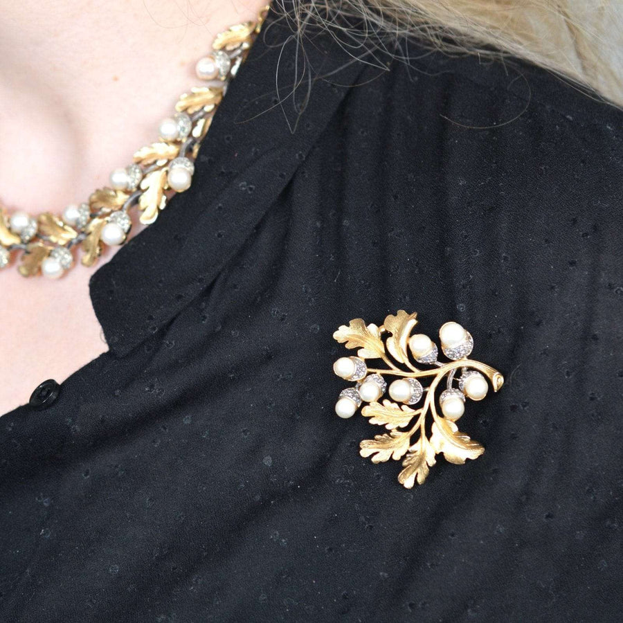Vintage 1950s Trifari gold-tone oak leaf brooch adorned with faux pearls, worn with matching necklace.