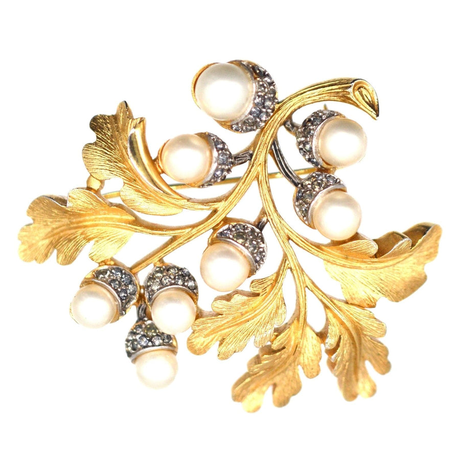 1950s Trifari gold-tone brooch featuring oak leaves, faux pearls, and rhinestones, part of a matching jewellery set.