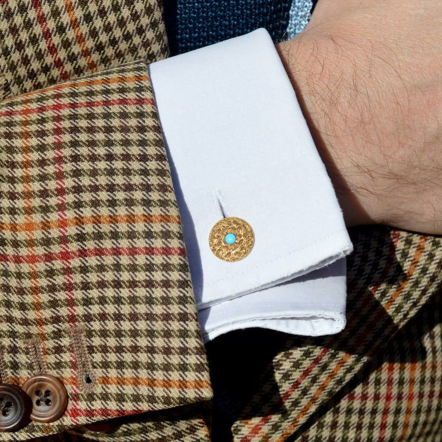 1960s textured gold cufflinks with turquoise detail worn on a checkered shirt cuff.
