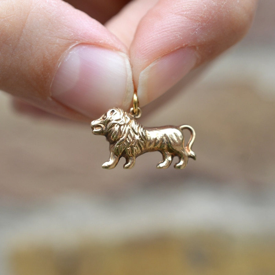 1960s 9ct gold lion charm pendant held in hand, symbolizing strength and courage.