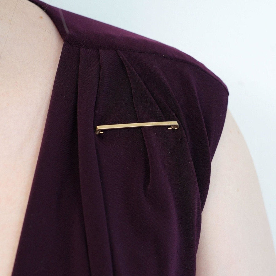 1960s 9ct gold flat bar brooch pinned on a purple dress, showcasing classic style and elegance.