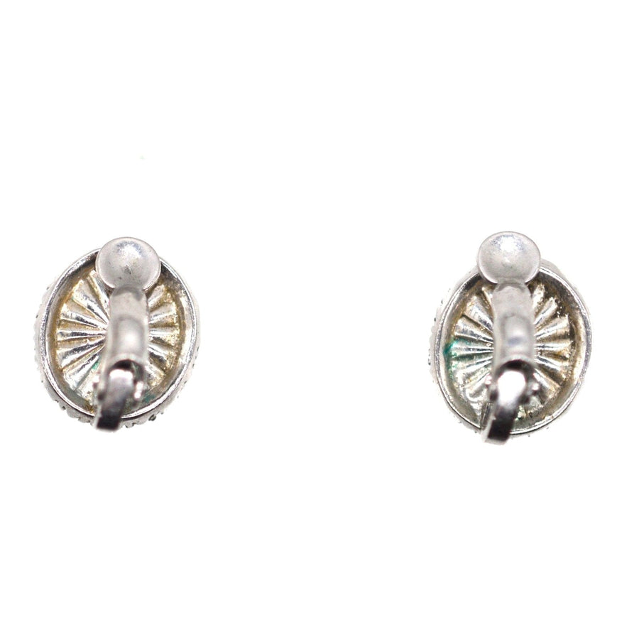 Vintage silver earrings with a sunburst design on a circular base.
