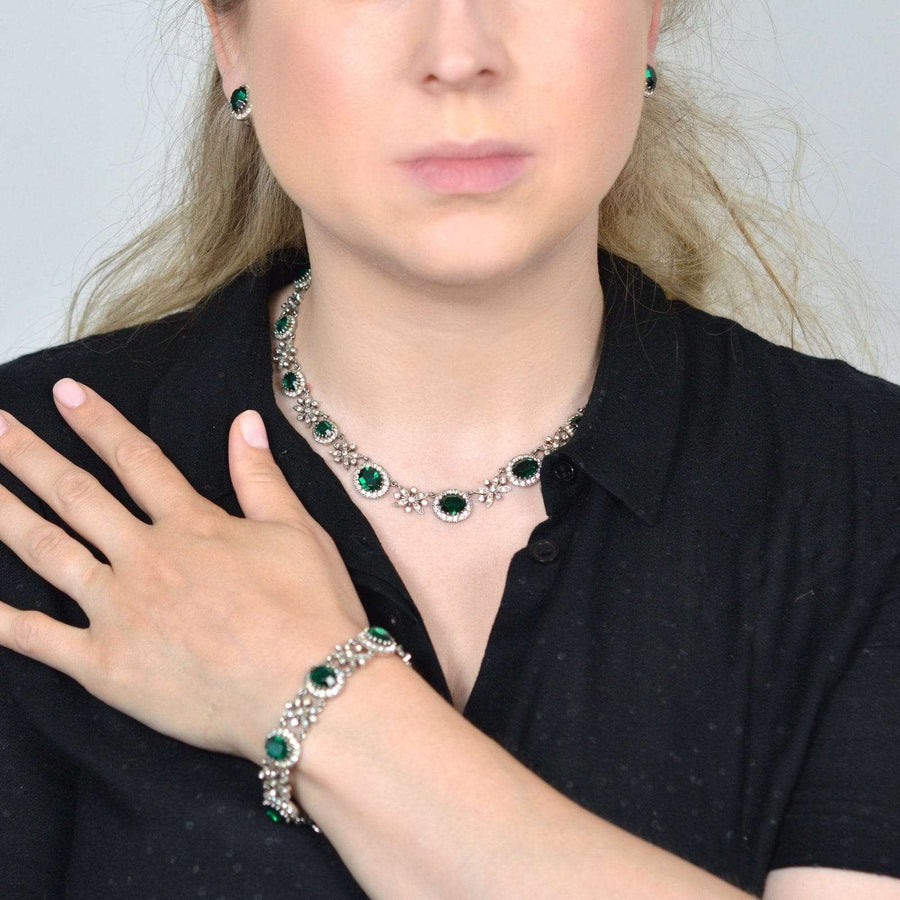 Model showcases a 1960s green tourmaline and diamond paste parure set including necklace, bracelet, and earrings.