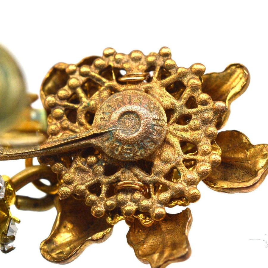 Close-up of 1960s Miriam Haskell faux pearl earrings showcasing intricate floral design and textured gold hardware.