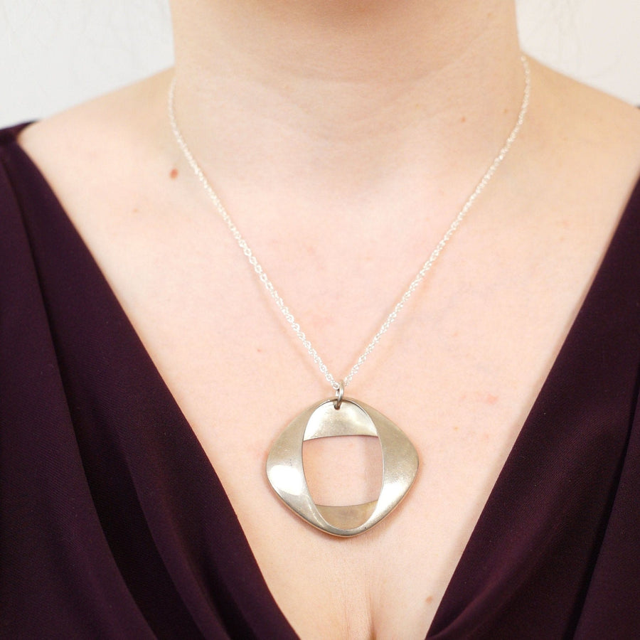 1960s silver modernist pendant by Henning Koppel for Georg Jensen, worn on a model's neck.