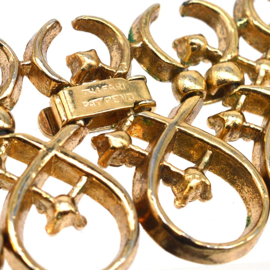1960s Trifari gold-tone necklace detail showcasing interlinked swirls and diamond pastes.