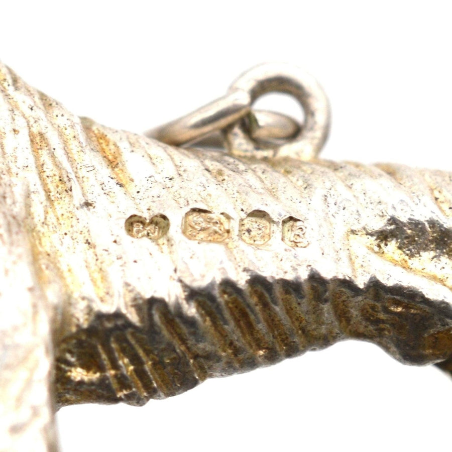 Close-up of a 1970s silver dog pendant showing detailed craftsmanship and hallmark stamps.