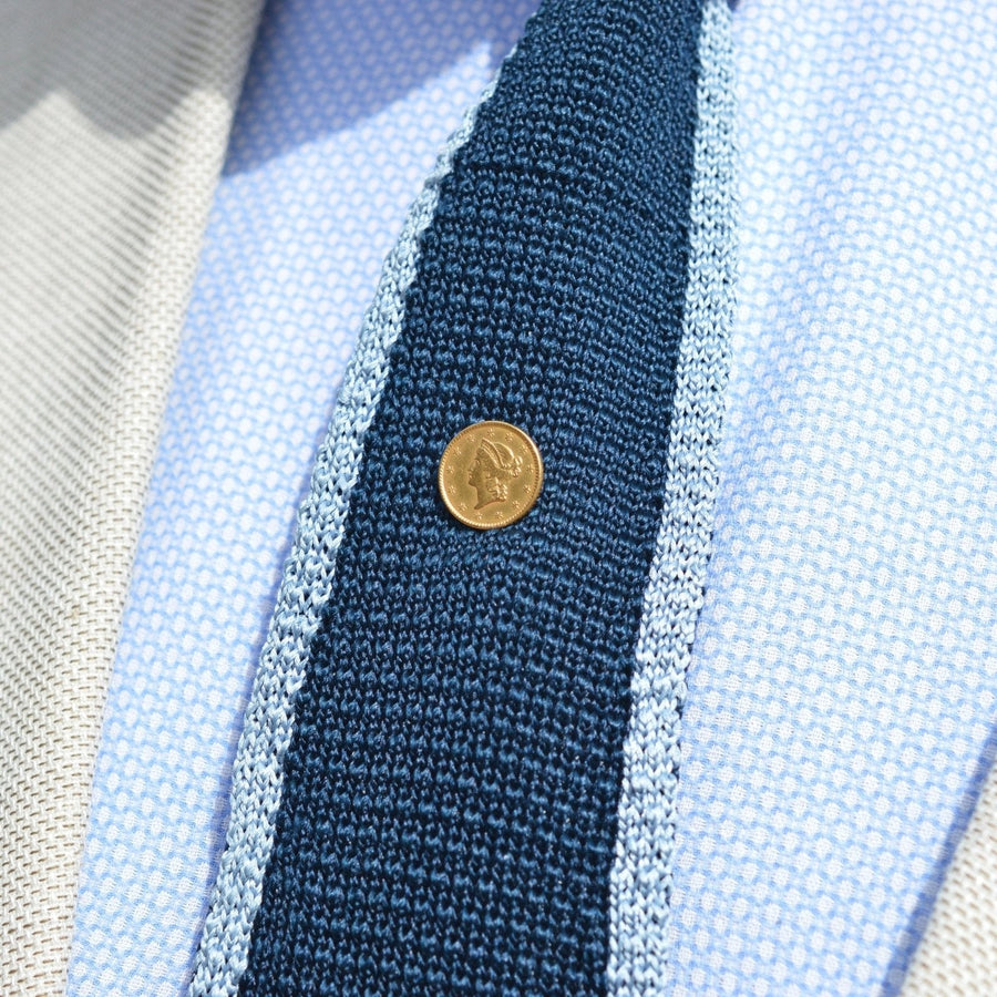 19th century gold $1 Liberty Head coin tie pin featured on a textured navy tie.