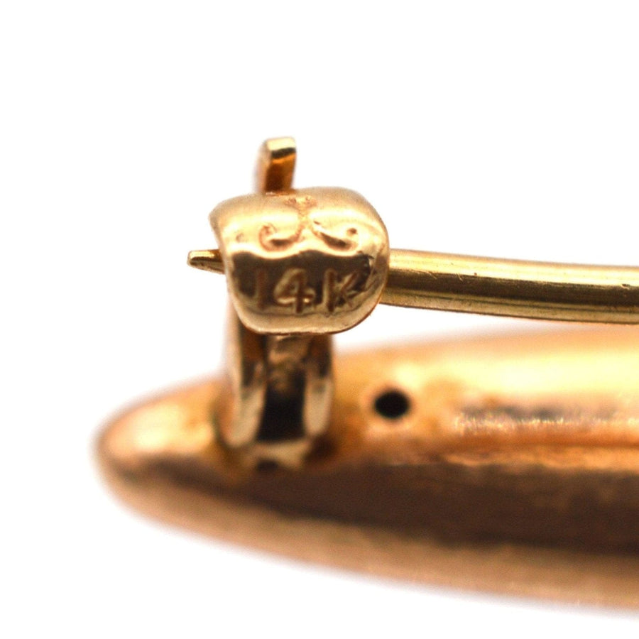 Close-up of 14ct gold hallmark on vintage baby girl brooch, highlighting quality craftsmanship and intricate design details.