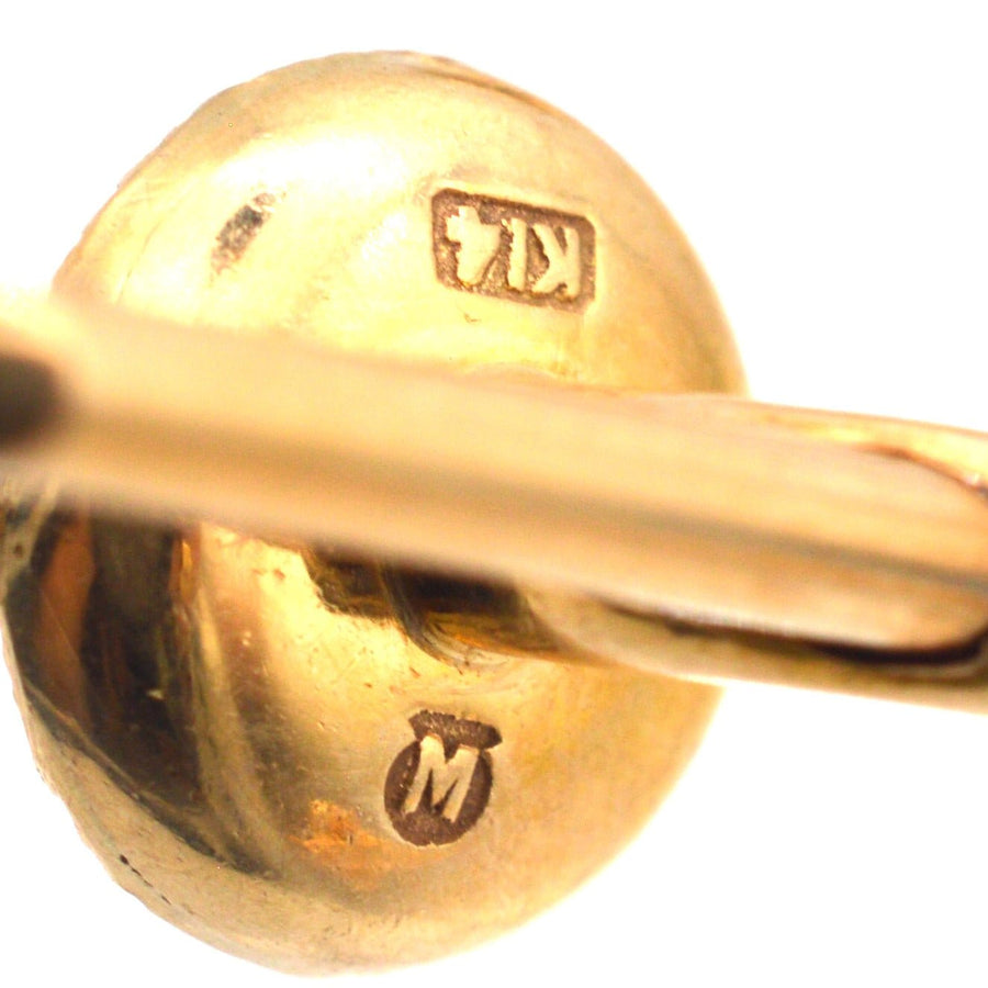 Close-up of a 14ct gold cufflink showing hallmarking and craftsmanship details.