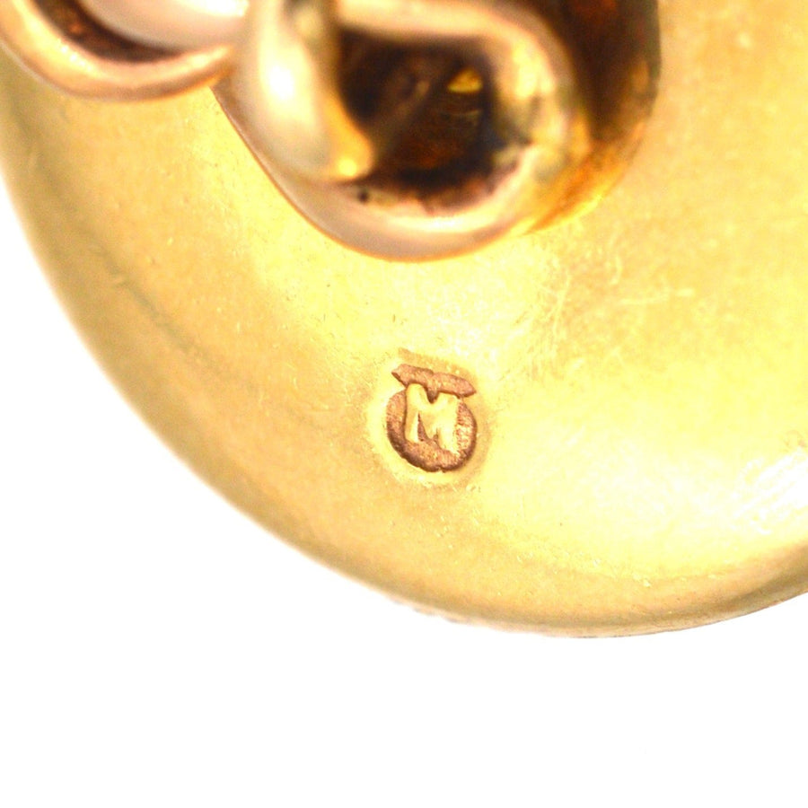 Close-up of the hallmark on a gold piece, showcasing the letter 'M' and the intricate design.