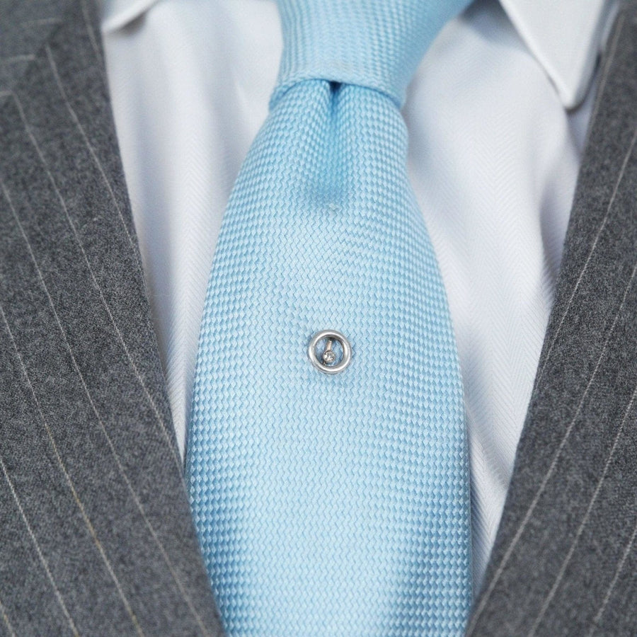 Art Deco 14ct gold and diamond circular tie pin featured on a light blue silk tie with a gray suit, showcasing elegance.
