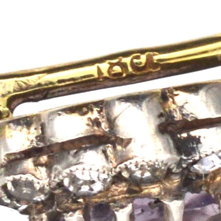 Close-up of an Art Deco 18ct gold tie pin featuring amethyst and white paste cluster design.