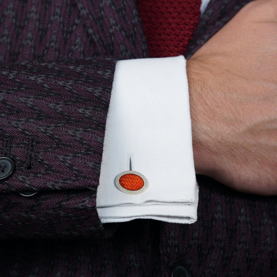 Close-up of a man's cuff with a vibrant red enamel Art Deco cufflink on a white shirt.