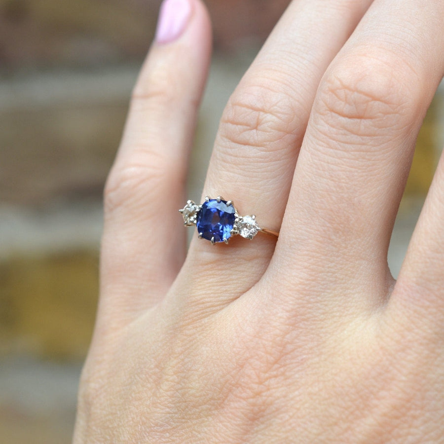 Art Deco 18ct gold and platinum three stone ring with sapphire and diamonds on a hand.