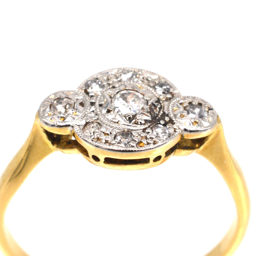 Art Deco 18ct gold and platinum three stone diamond halo design ring with intricate detailing.