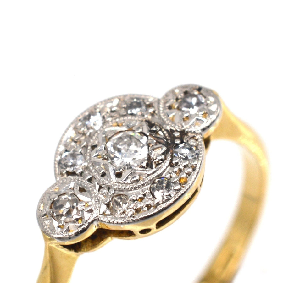 Art Deco 18ct gold and platinum three stone diamond halo design ring with intricate detailing.